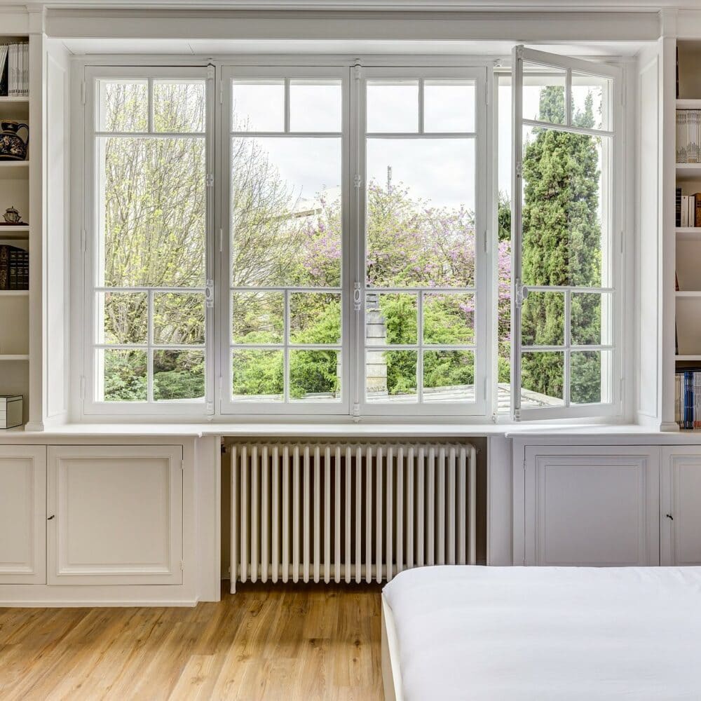 Chambre avec grande bibliothèque intégrée et fenêtre ouvrante.