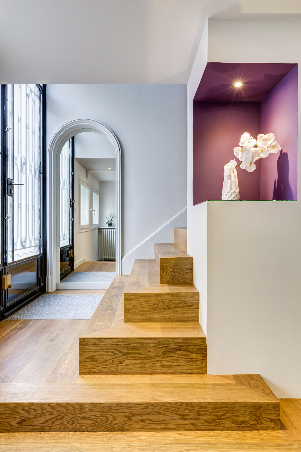 Entrée avec escalier en bois et alcôve décorative violette.