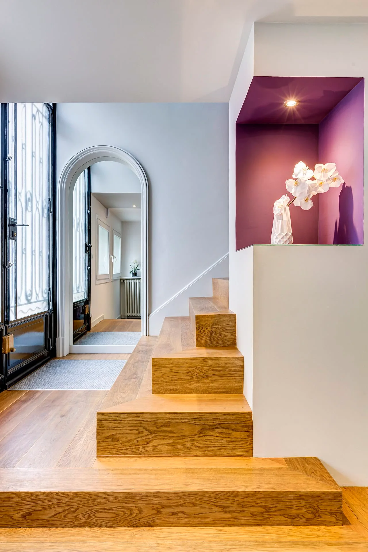 Entrée avec escalier en bois et alcôve décorative violette.