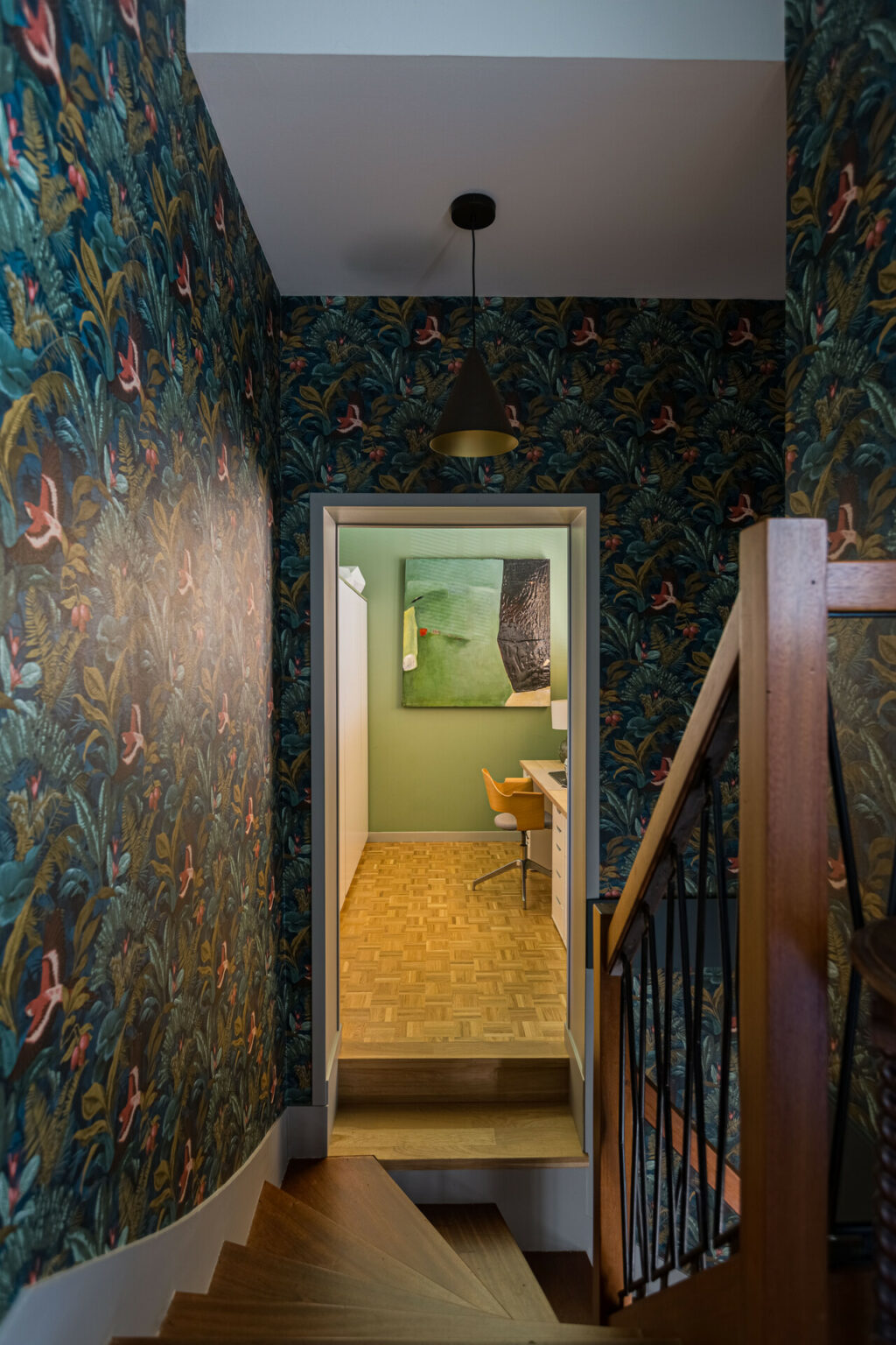Escalier avec papier peint jungle menant à un bureau vintage au mur vert.