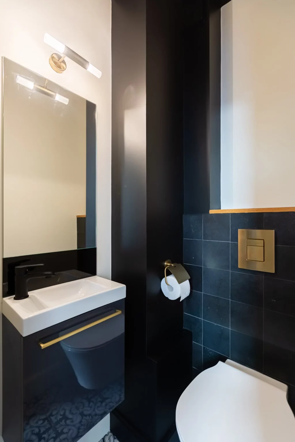 Salle de bain moderne avec carrelage bleu foncé, robinetterie dorée et ambiance élégante à Bordeaux.