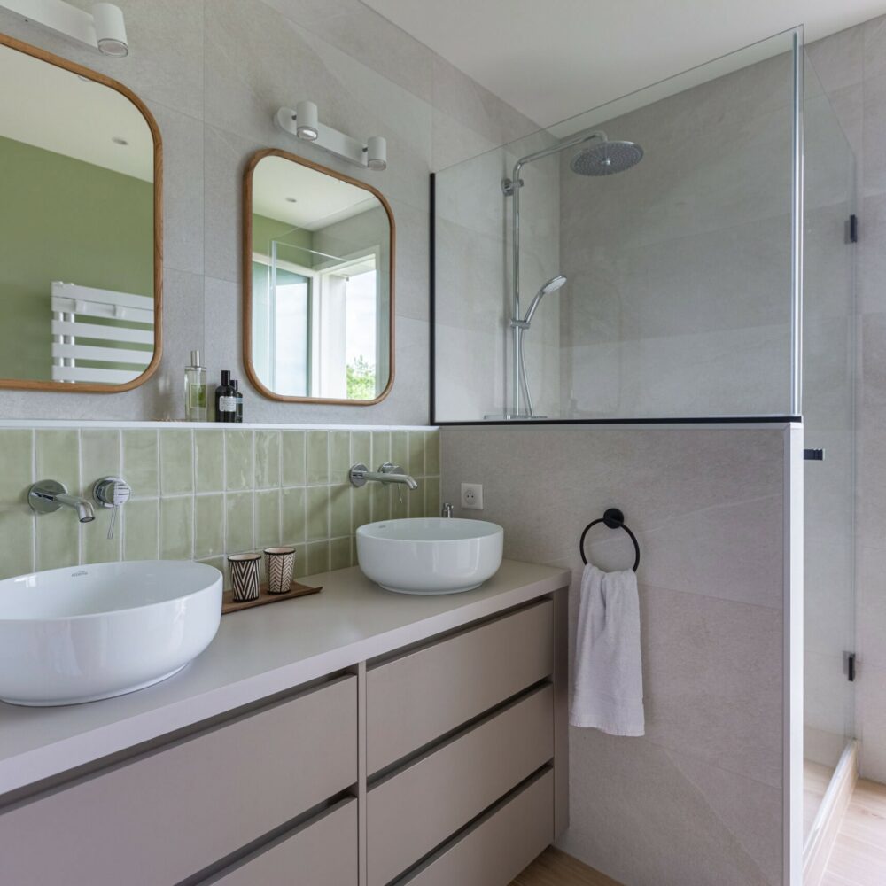 Salle de bain avec double vasque, miroirs en bois et douche à l’italienne avec paroi vitrée