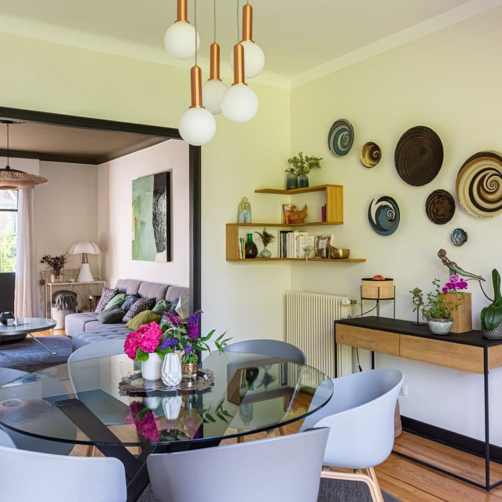 Salle à manger avec décoration murale et vue sur un salon lumineux