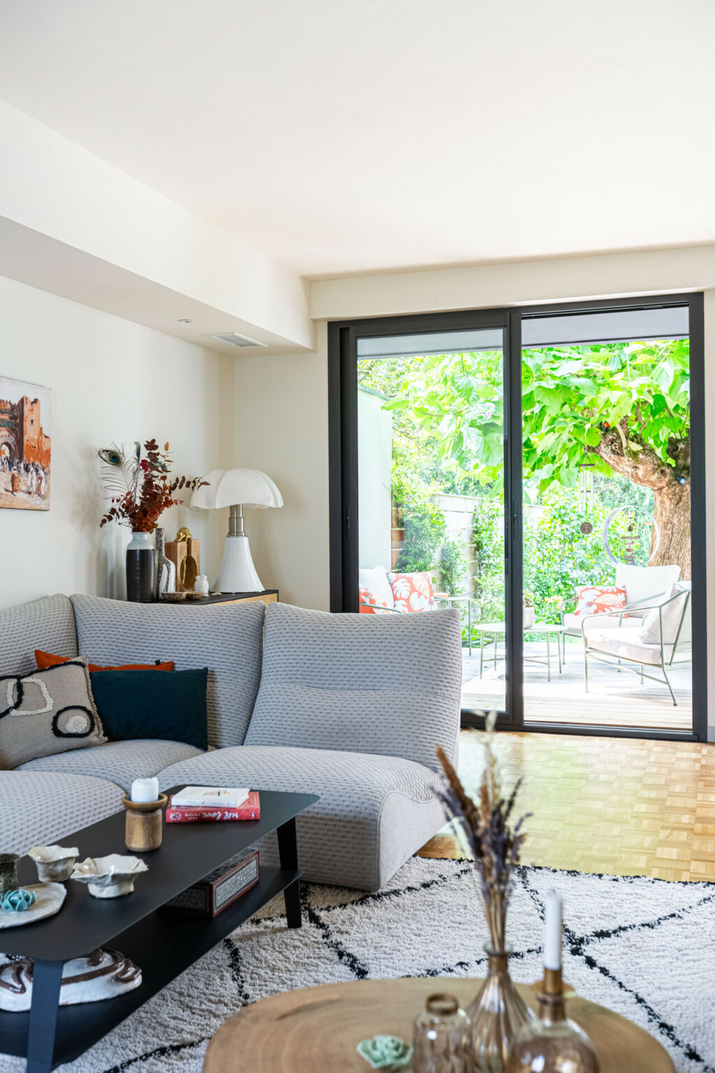 Salon contemporain avec grande baie vitrée donnant sur une terrasse ombragée.