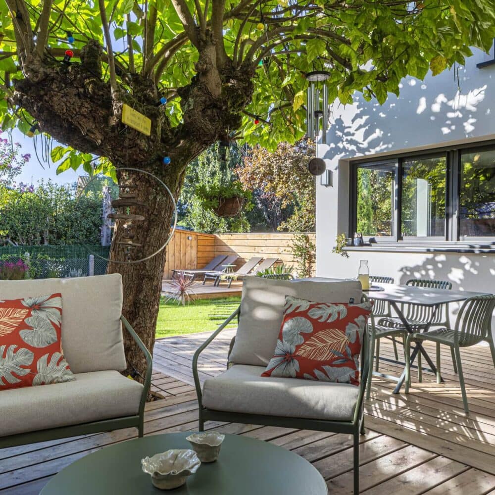 Terrasse en bois aménagée avec salon extérieur et vue sur le jardin et la piscine.