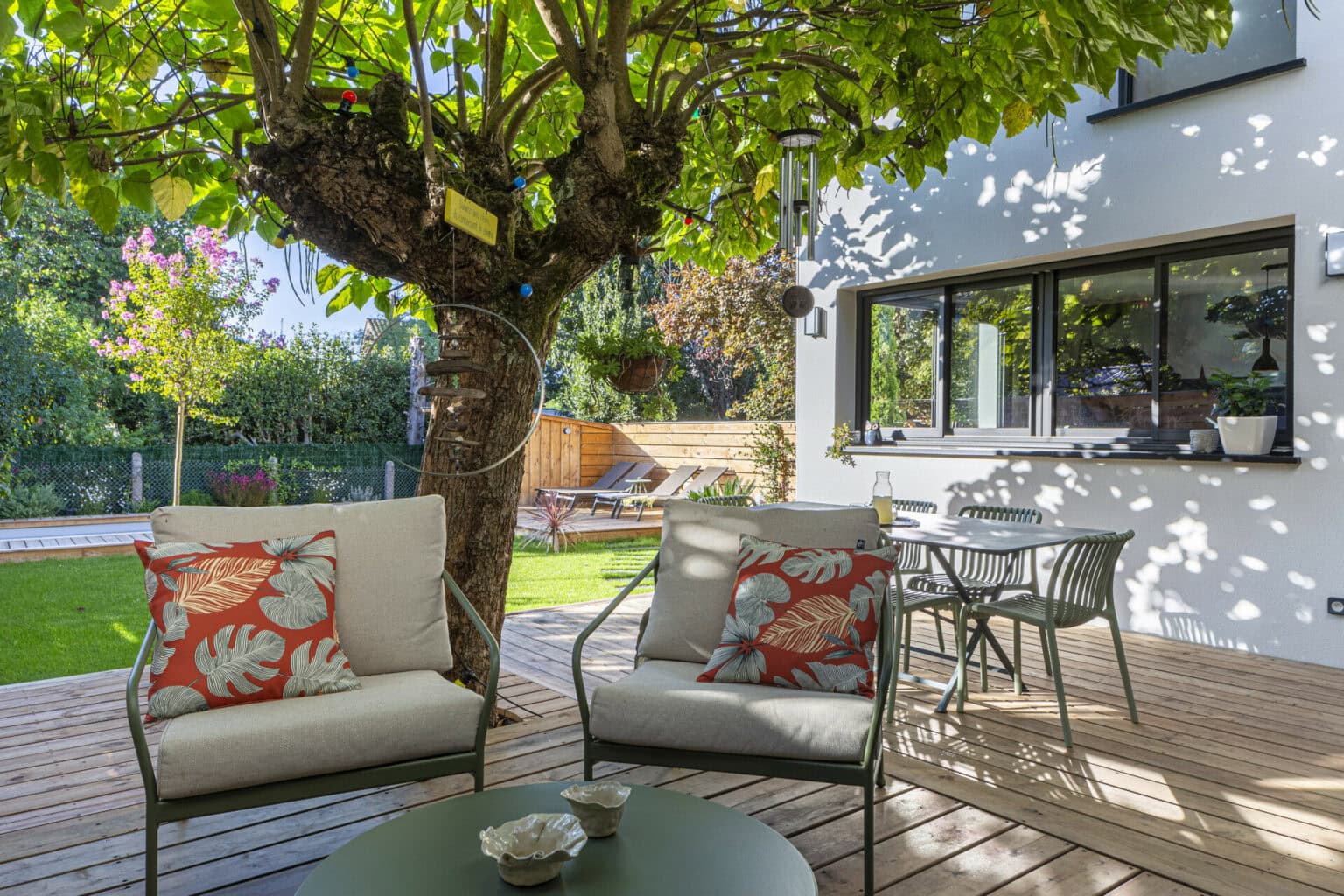 Terrasse en bois aménagée avec salon extérieur et vue sur le jardin et la piscine.