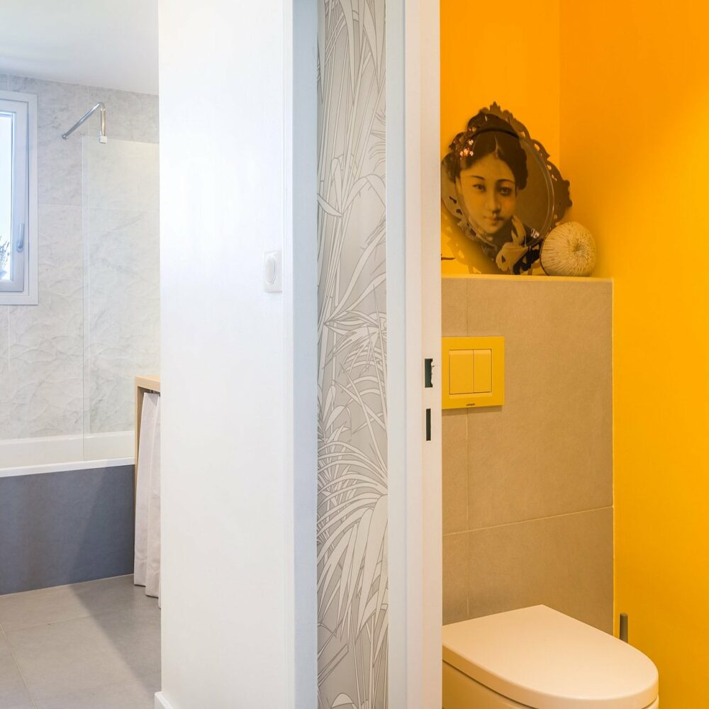 Toilettes avec mur jaune vif et décoration murale artistique