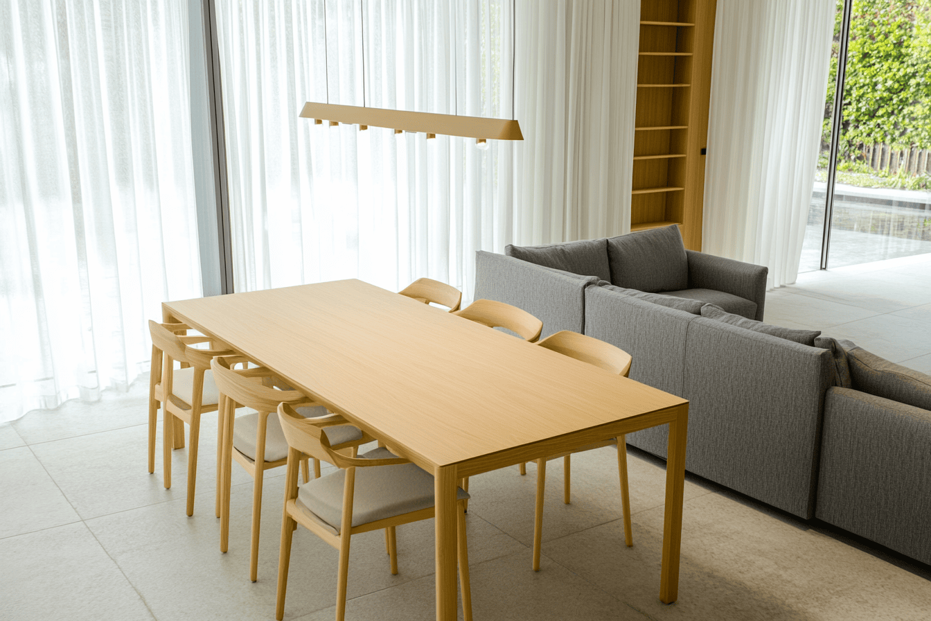 Table à manger extensible en bois clair, chaises à pieds fins et canapé droit à proximité